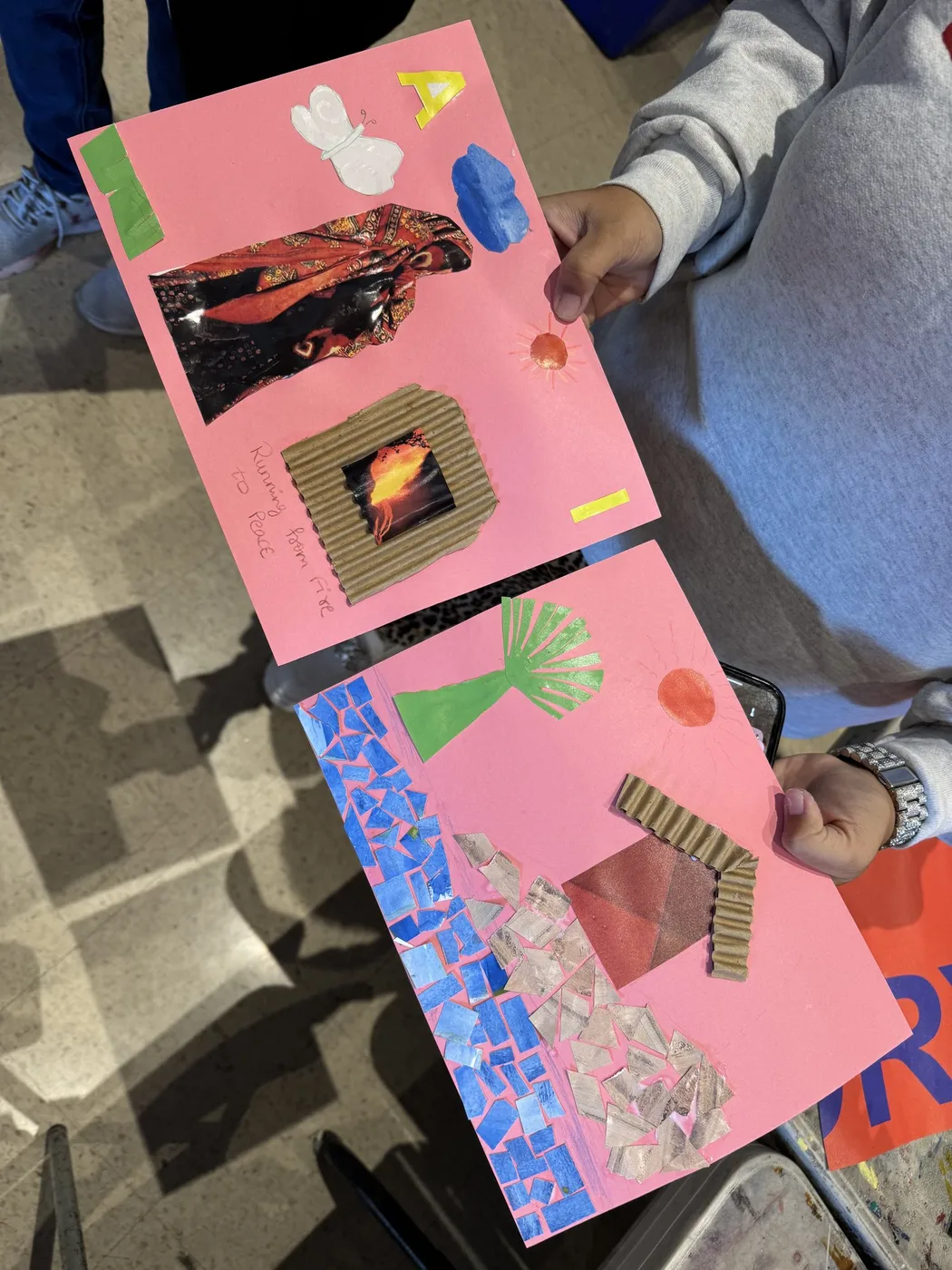 Adult hands holding two pink paper collages