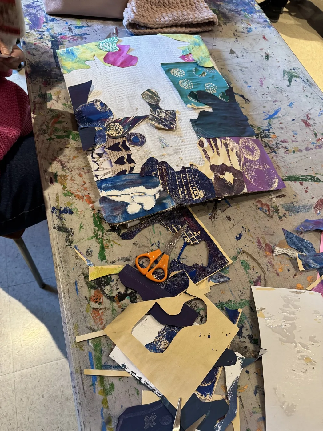 Printed-paper collage in progress on a paint-stained table
