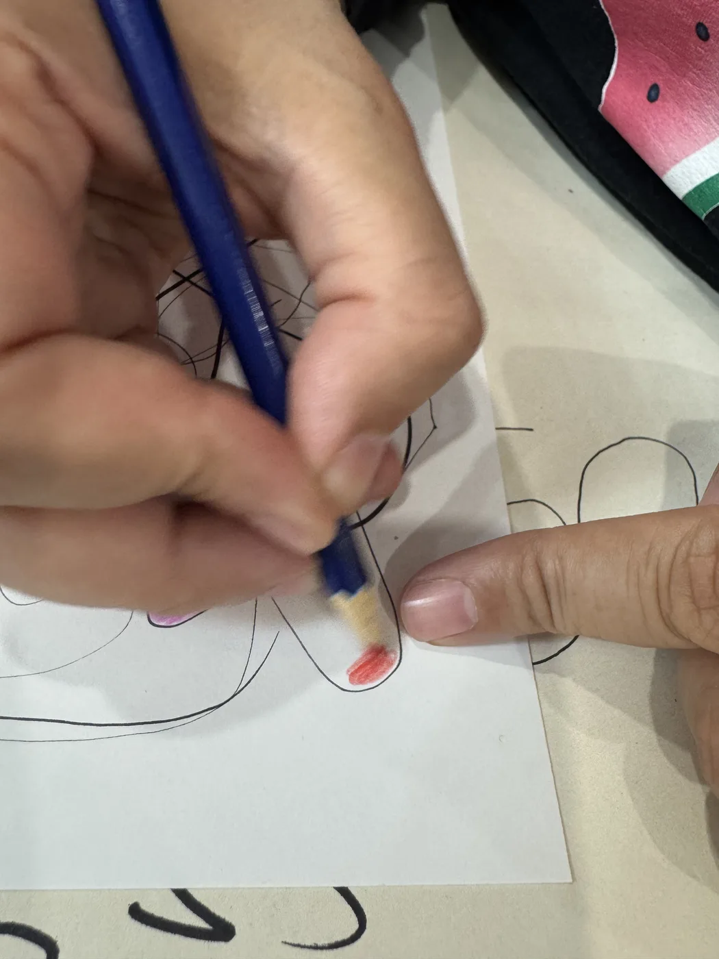 Adult hands colouring a doodle with pencil crayons
