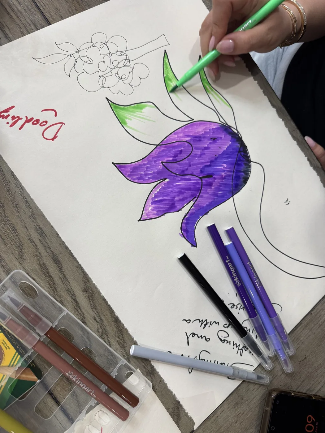 Adult hand colouring a purple tulip doodle