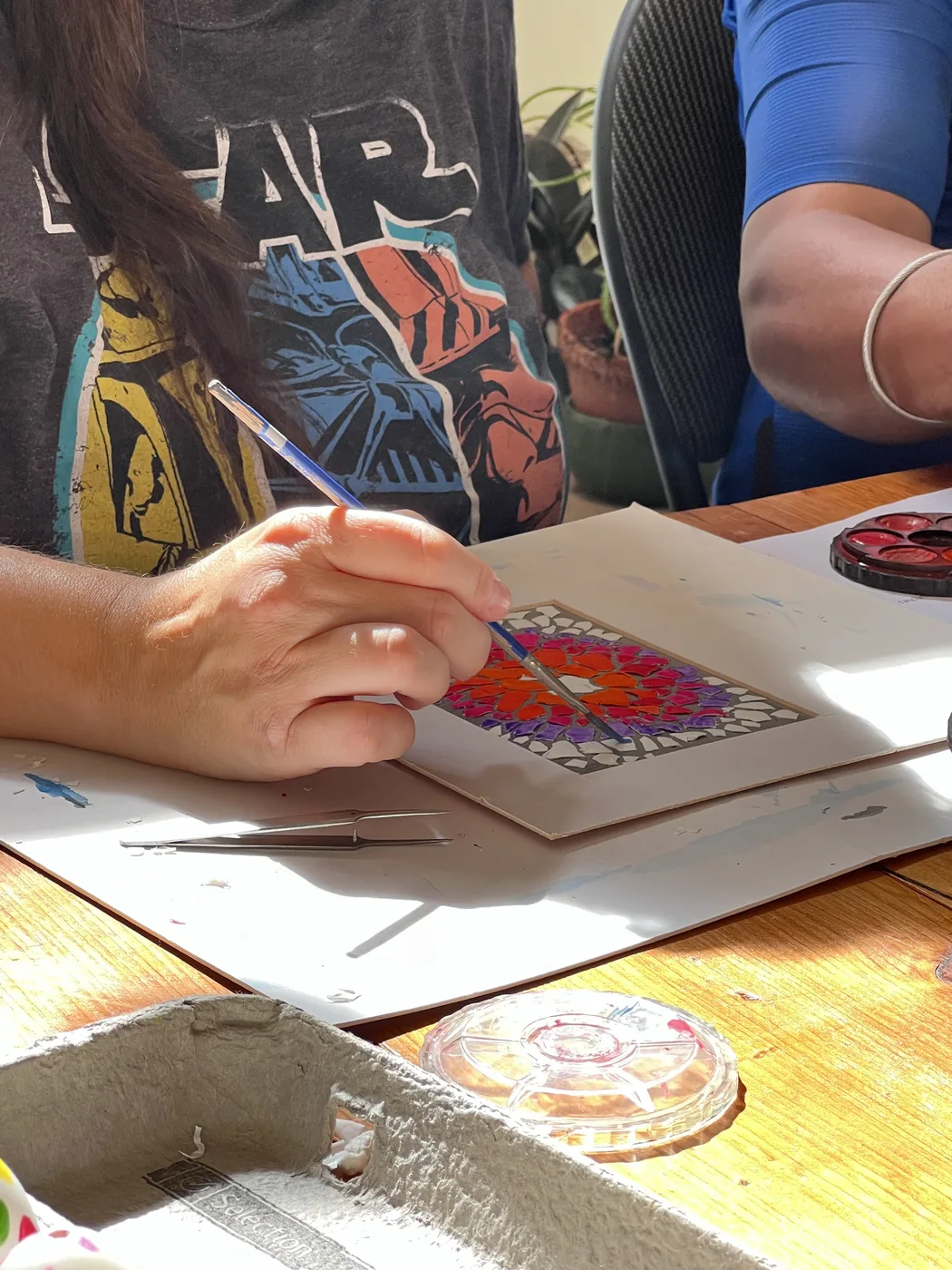 Adult hand painting an eggshell mosaic
