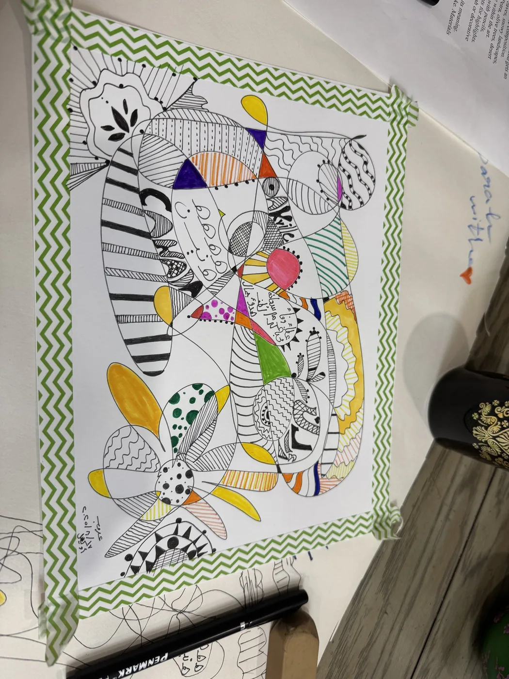 Black-and-white doodle with coloured patches in a striped frame
