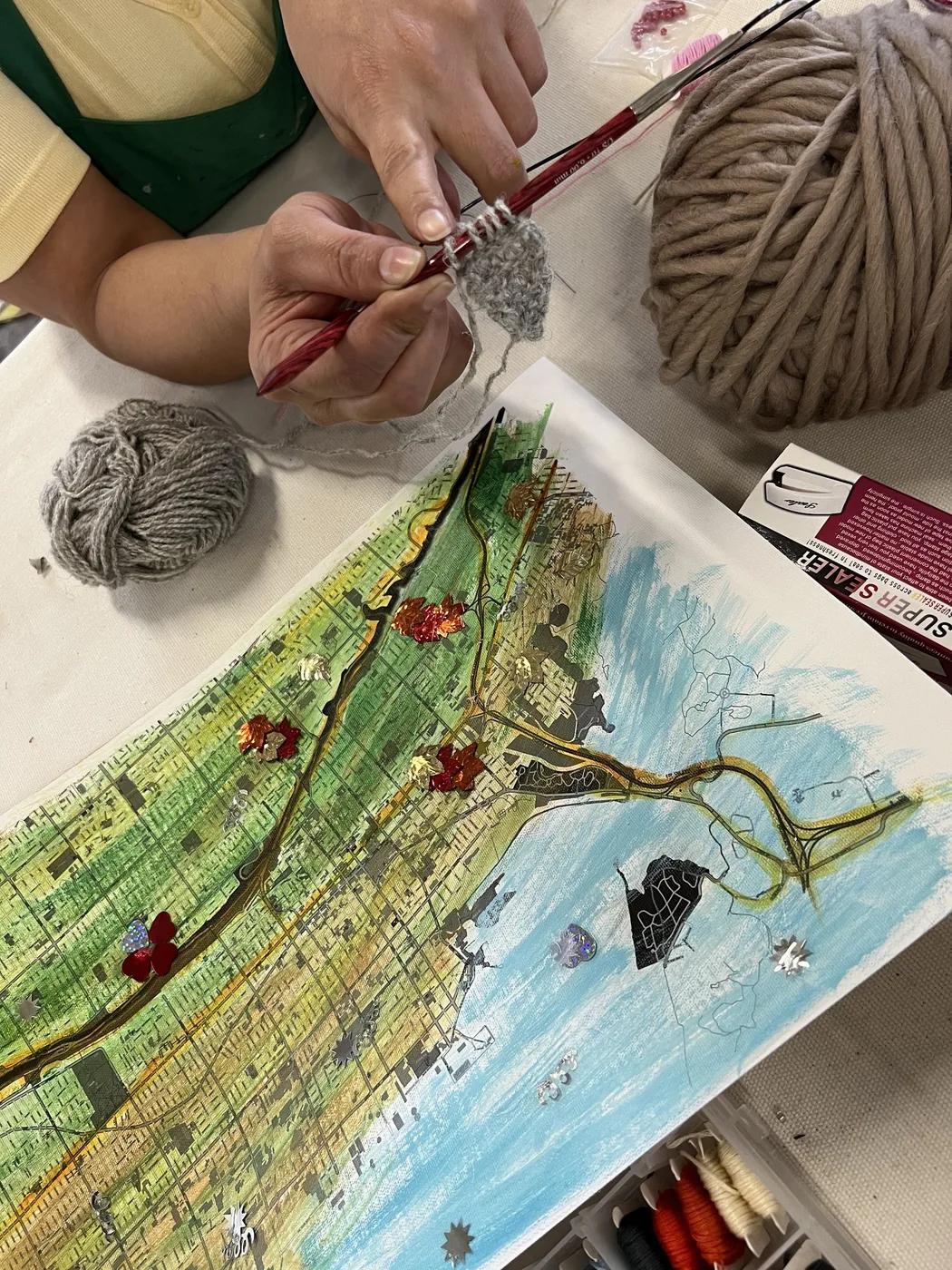 Adult hands adding yarn to a painted map