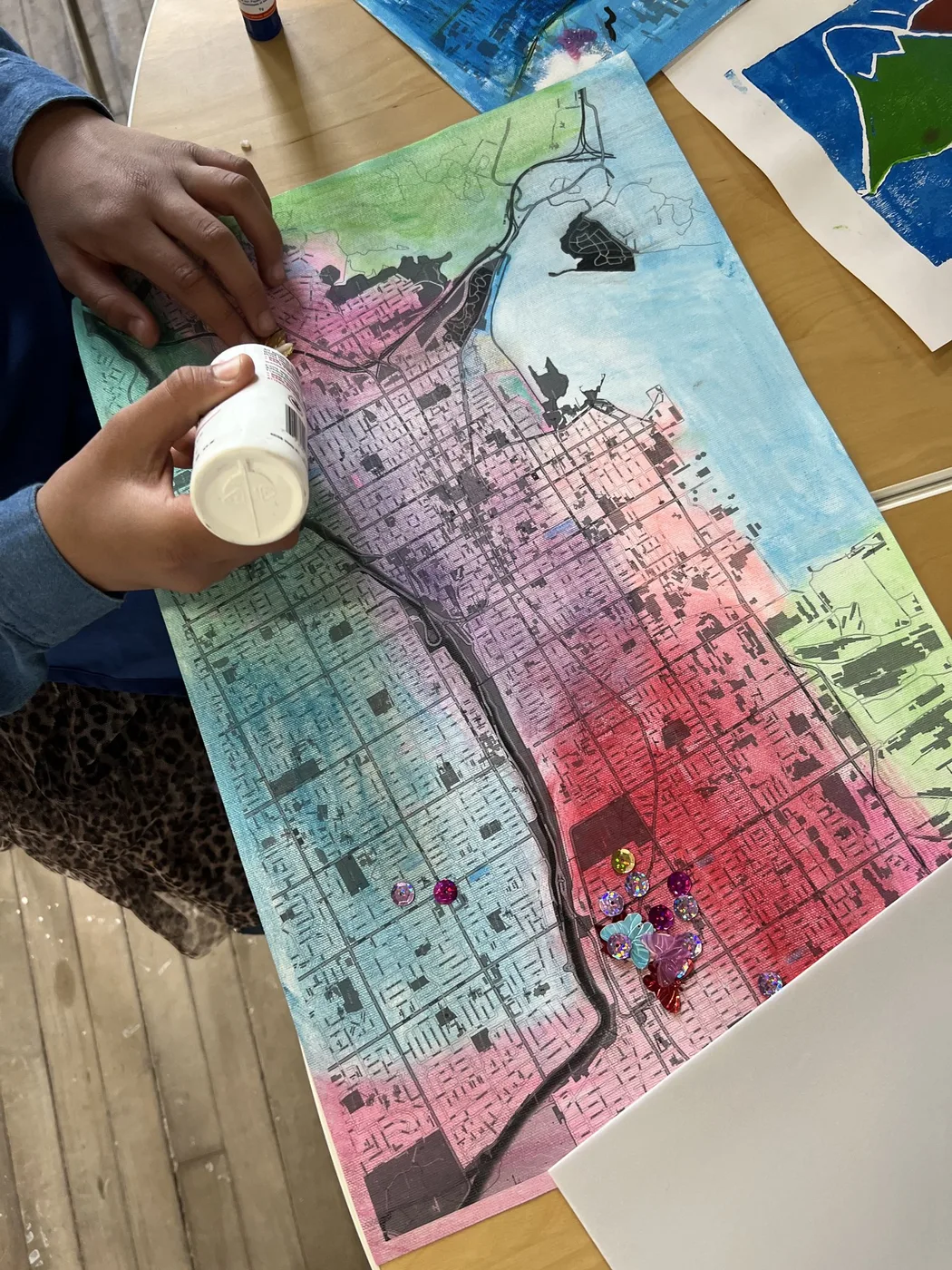 Adult hands gluing sequins on a painted map