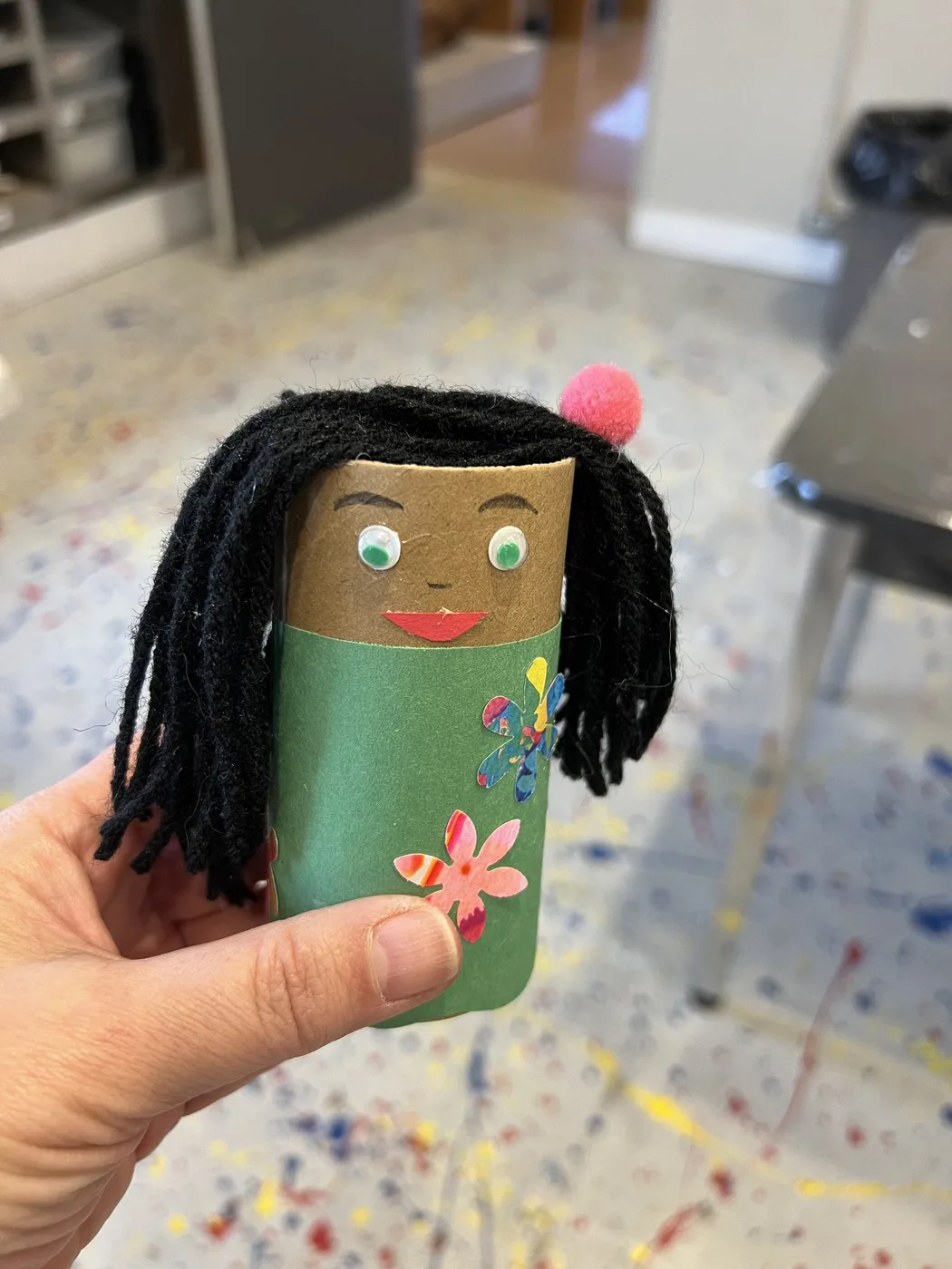 Adult hand holding a tube doll with yarn hair