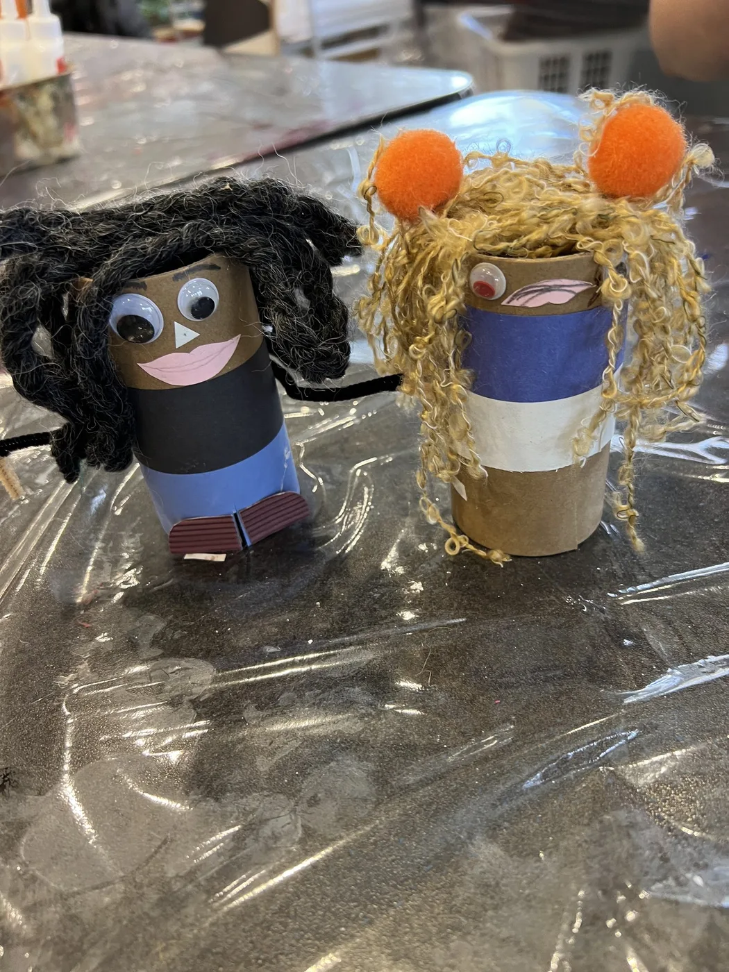 Two tube dolls with yarn hair and pompoms