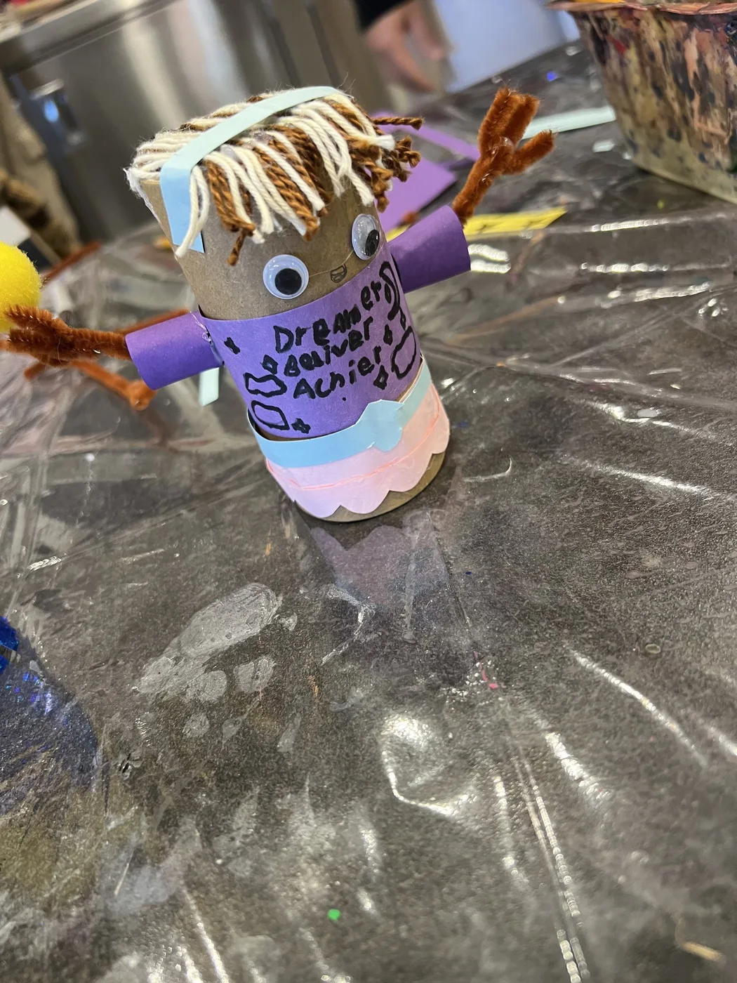 Tube doll with yarn fringe and ’Dreamer’ written shirt