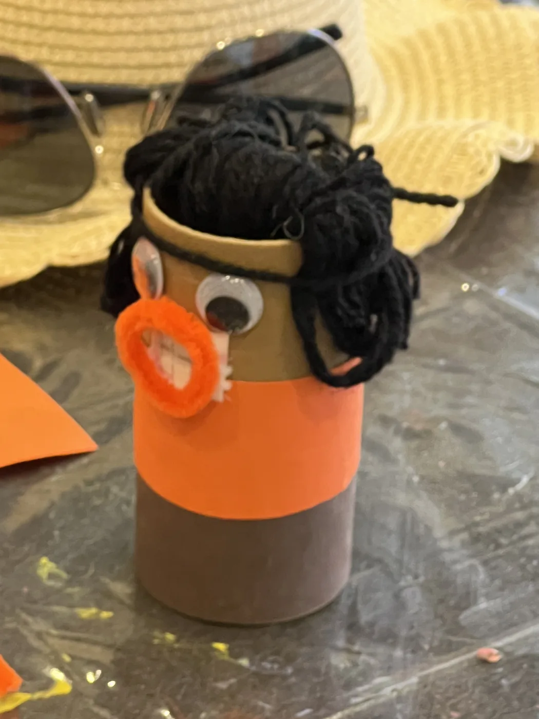 Tube figure with black yarn hair and orange mouth