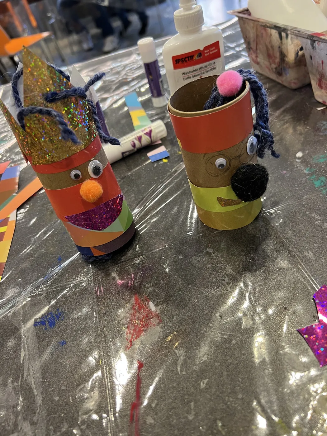 Two tube figures with yarn hair and pompom noses