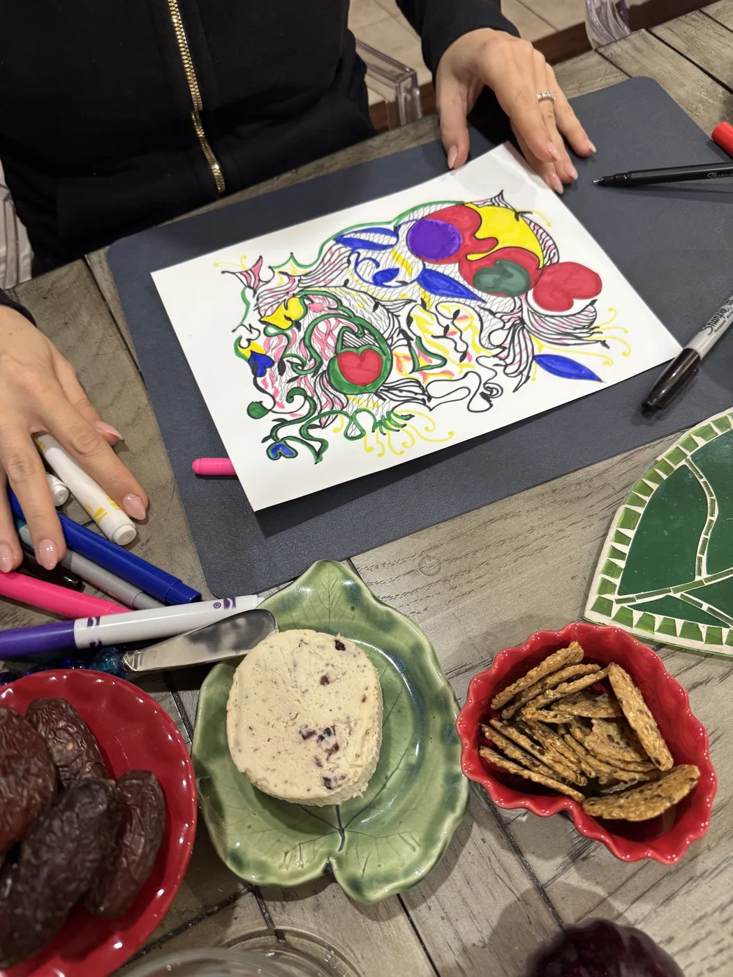 Adult hands beside a doodle, dates and snacks