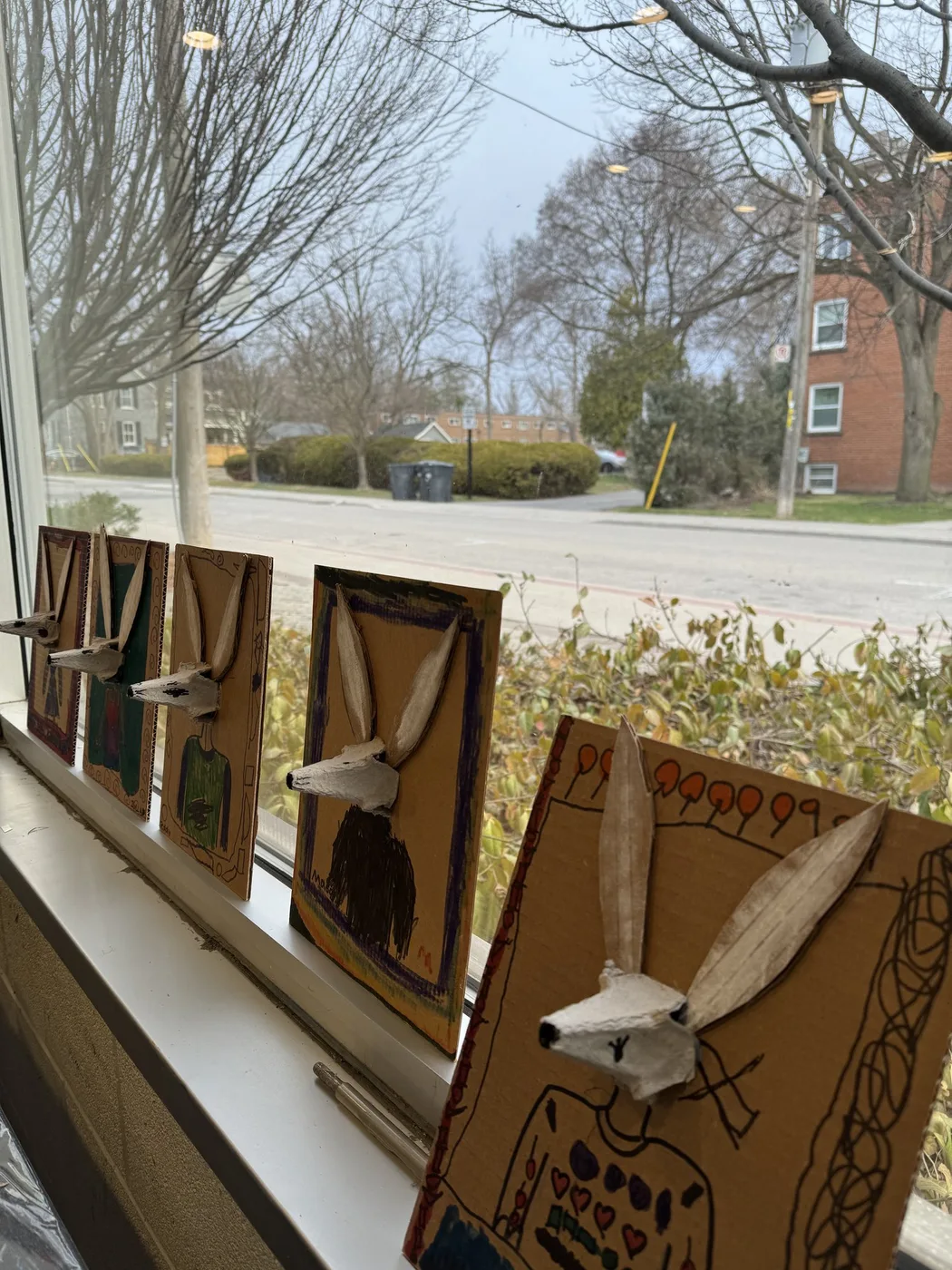 Cardboard hare portraits lined up on a windowsill