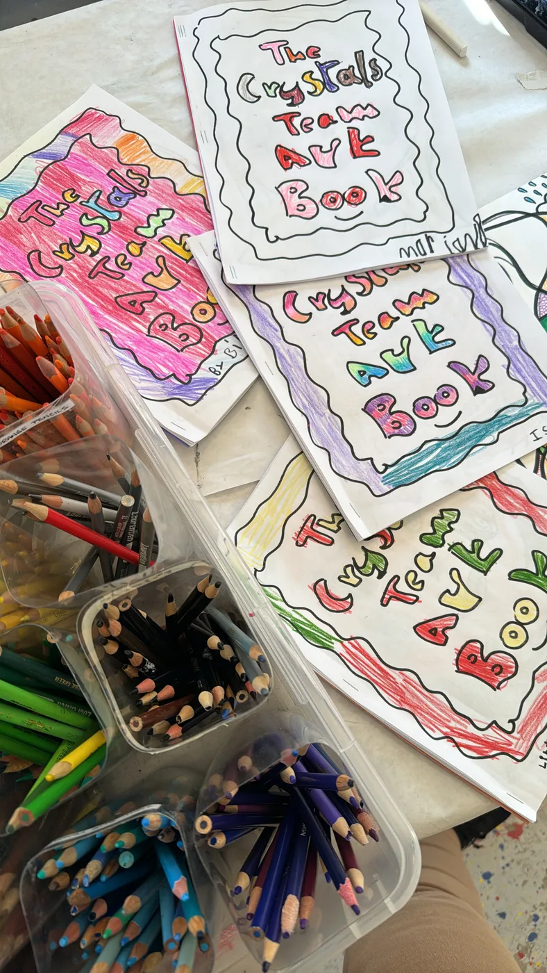 Hand-lettered team art books beside pencil tubs