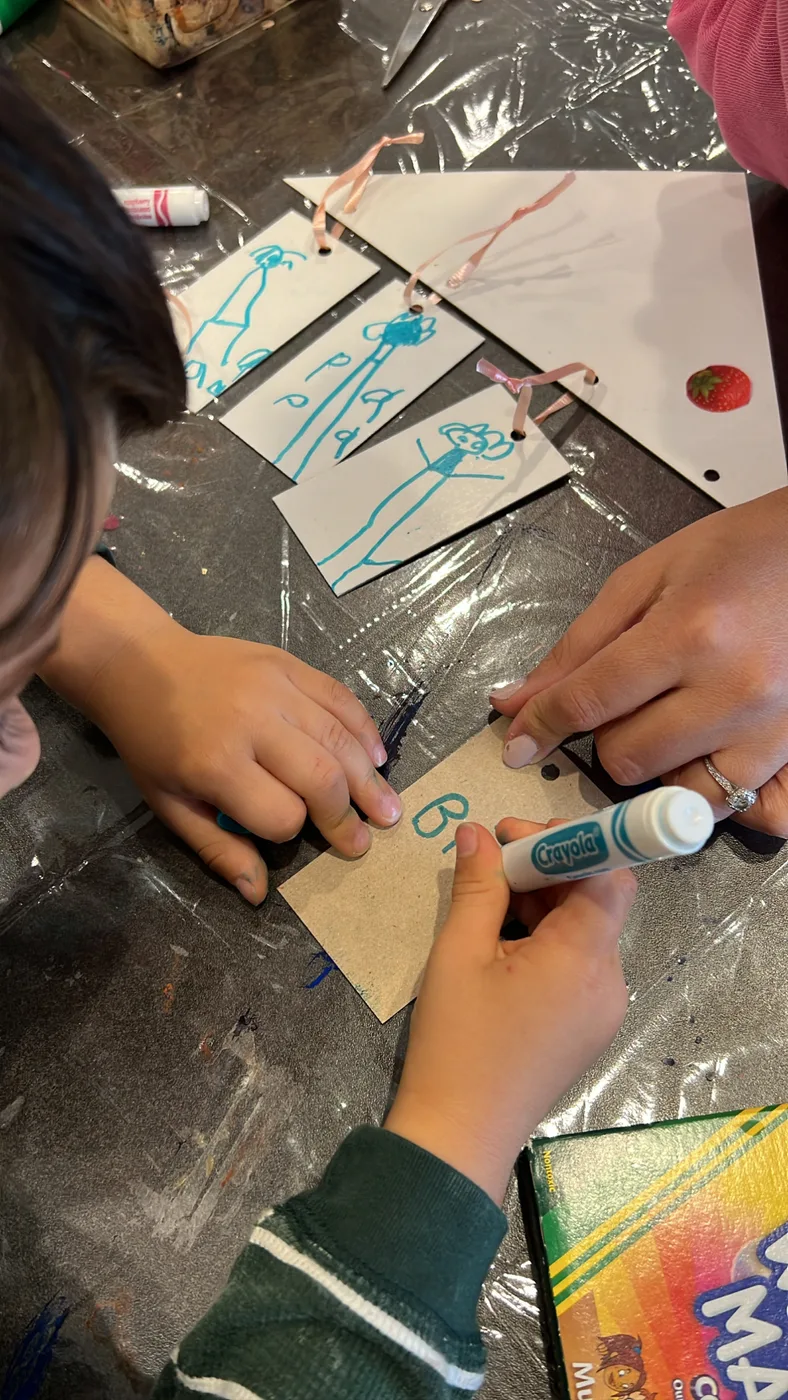 Small hands drawing on paper tags with markers