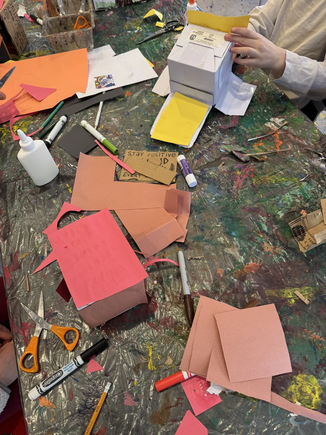 Paper box characters being built on a messy table