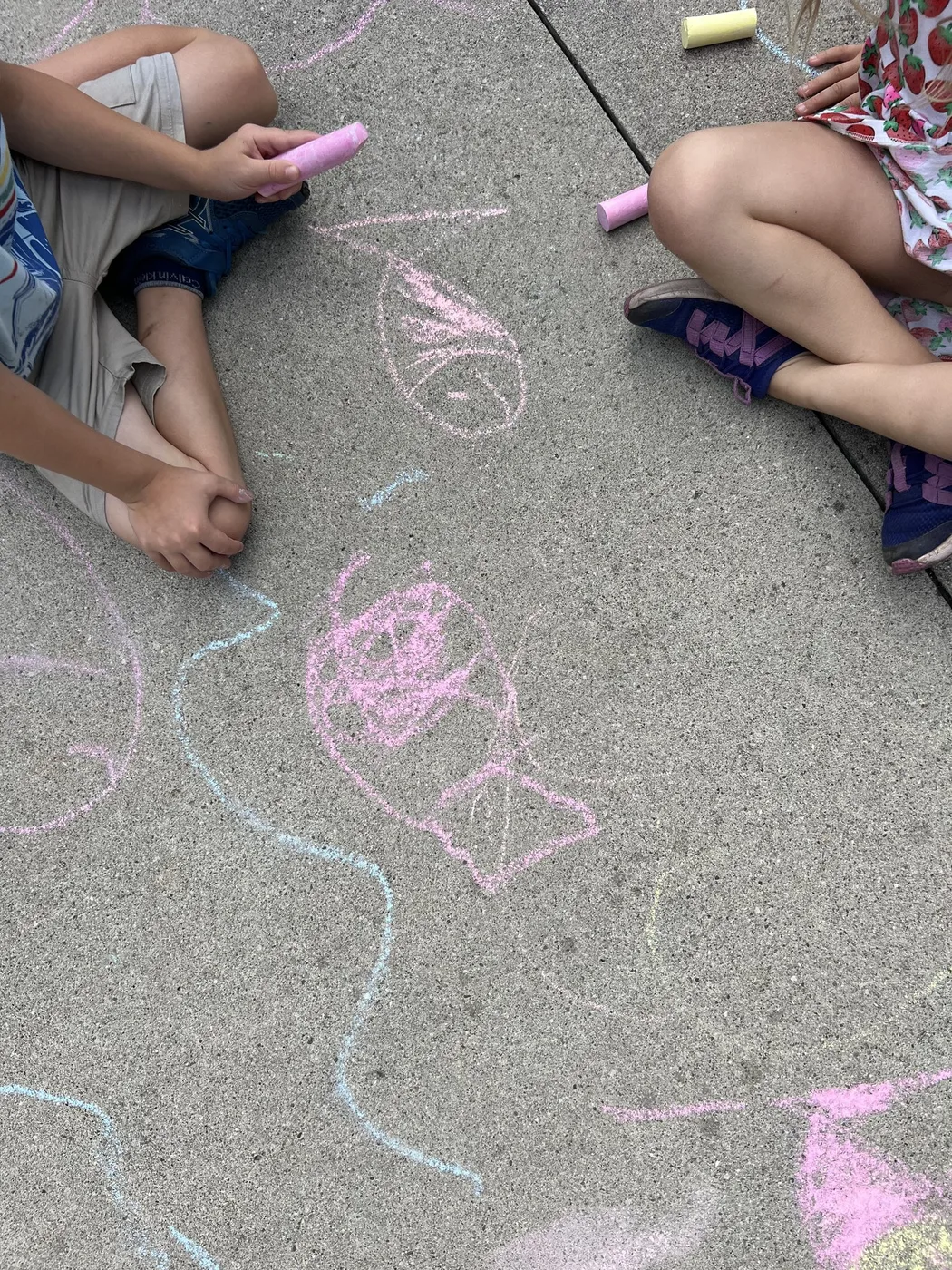 Chalk fish drawn on pavement beside crossed legs