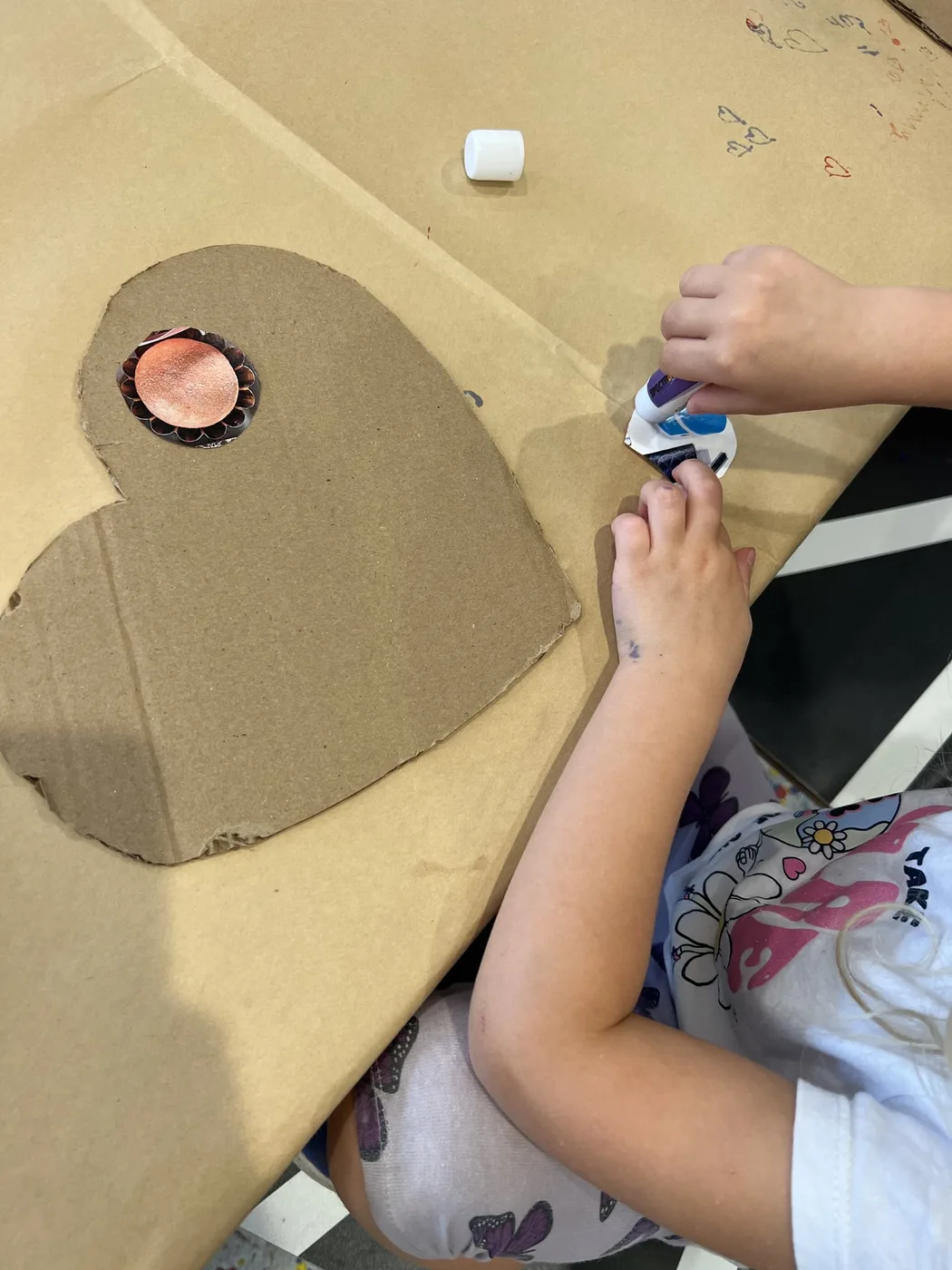 Hands decorating a cardboard heart