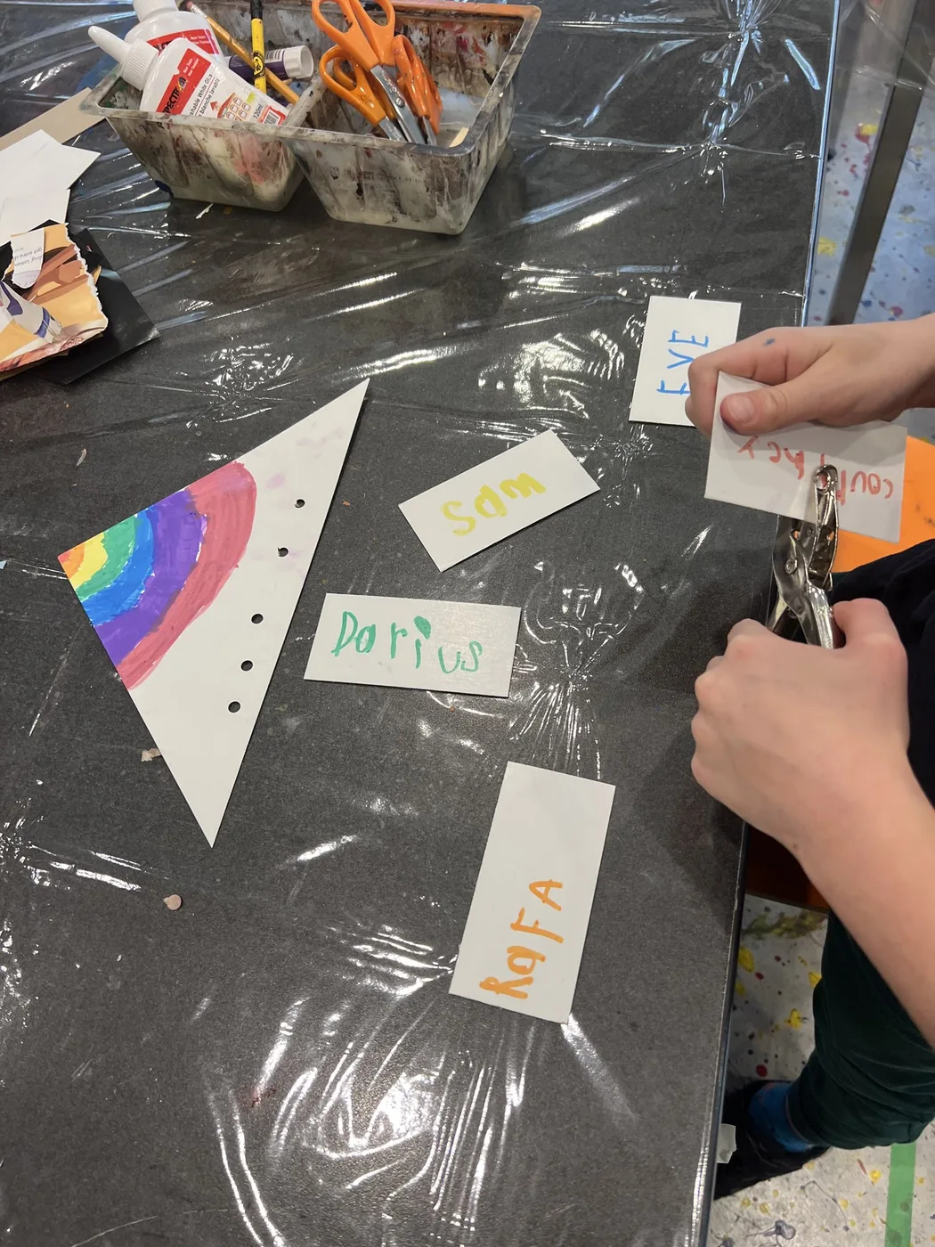 Hands punching holes in name tags and pennants