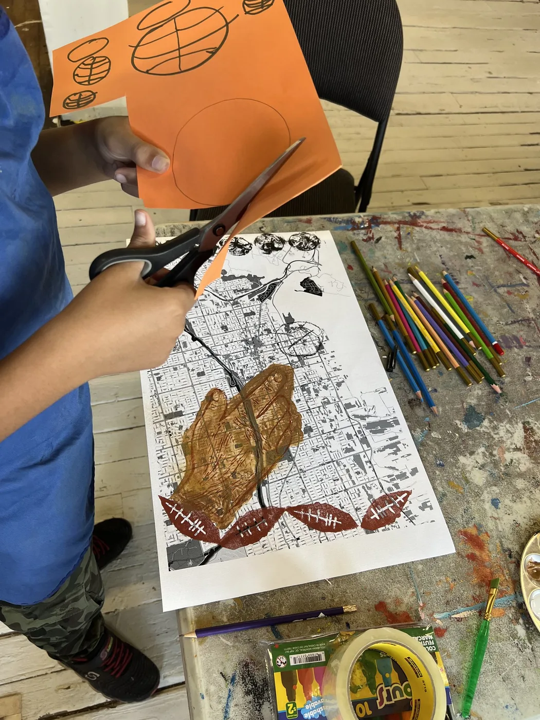 Hands cutting orange paper over a map drawing