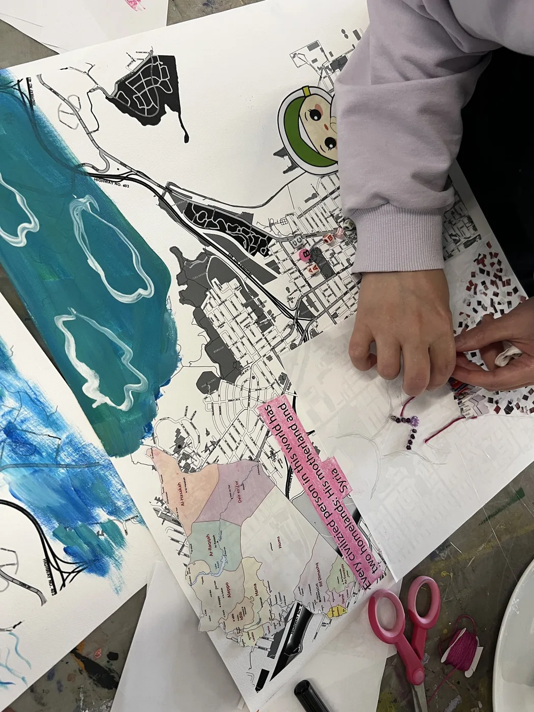 Hands adding beads to a painted map collage