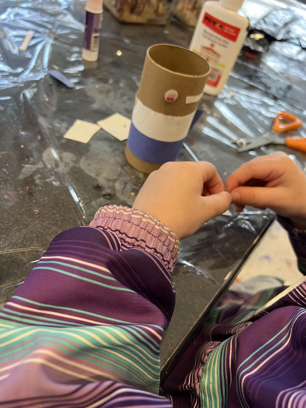 Hands wrapping paper around a cardboard tube
