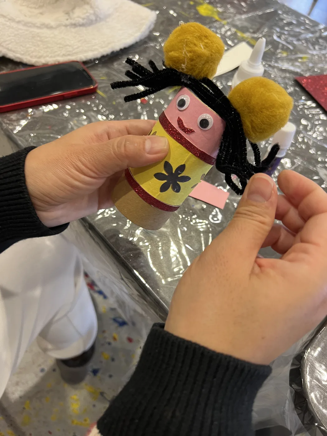 Hands holding a tube doll with pom-pom buns