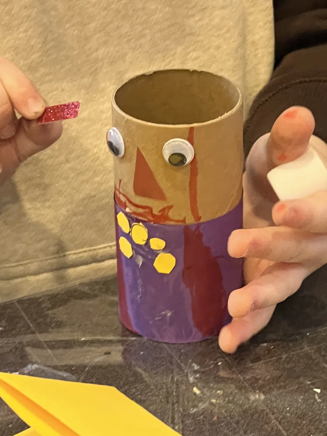 Hands decorating a purple tube character