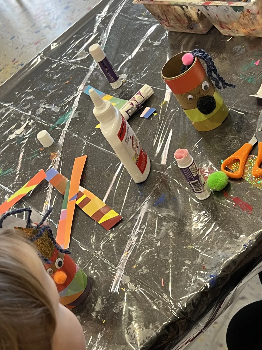 Tube character, glue and paper strips on a table