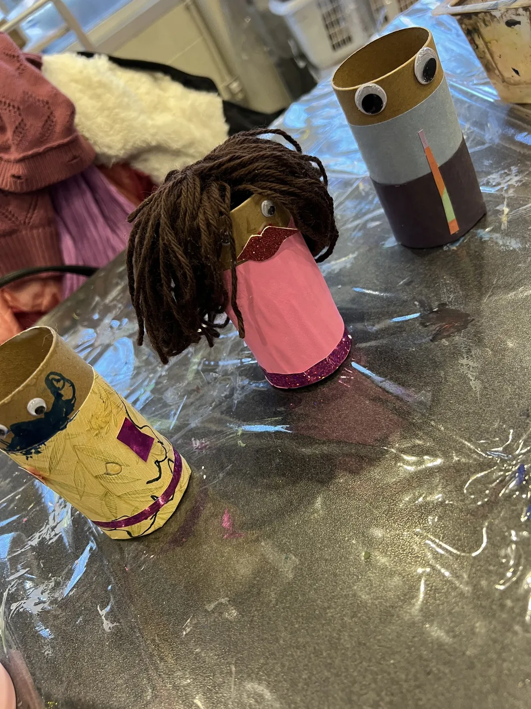 Three tube characters with yarn hair and googly eyes