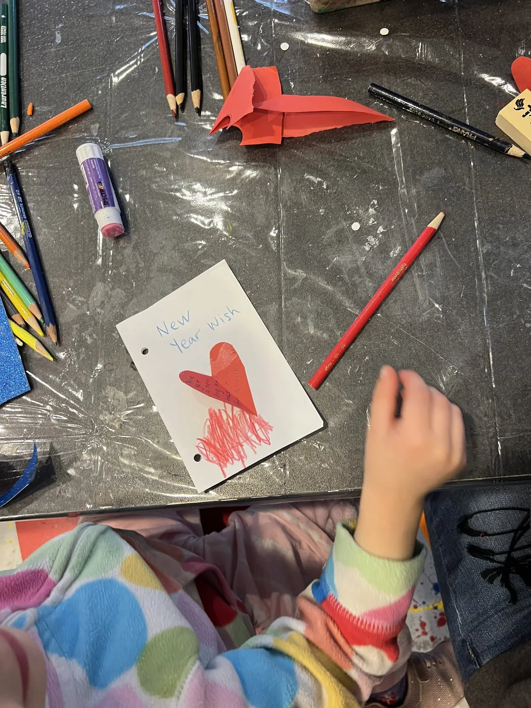 Paper heart wish card beside coloured pencils