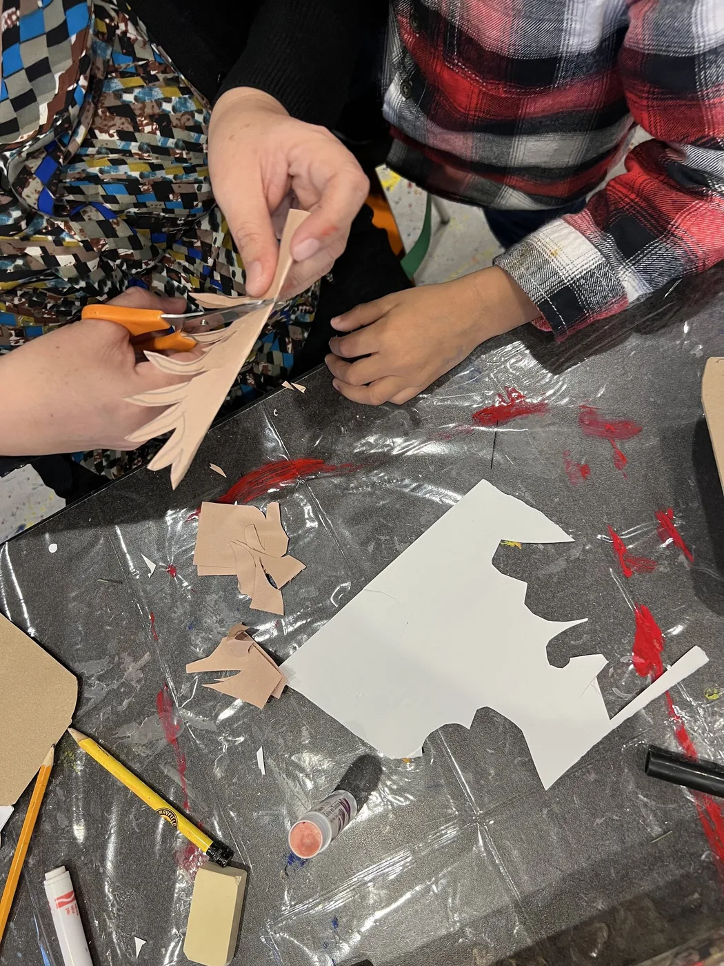 Hands cutting skin-tone paper shapes