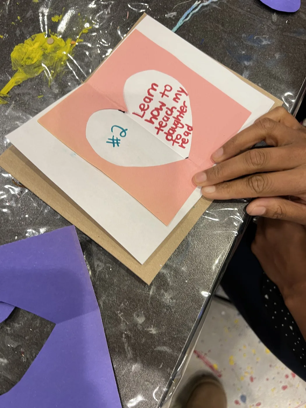 Hands holding a pink pop-up heart wish page