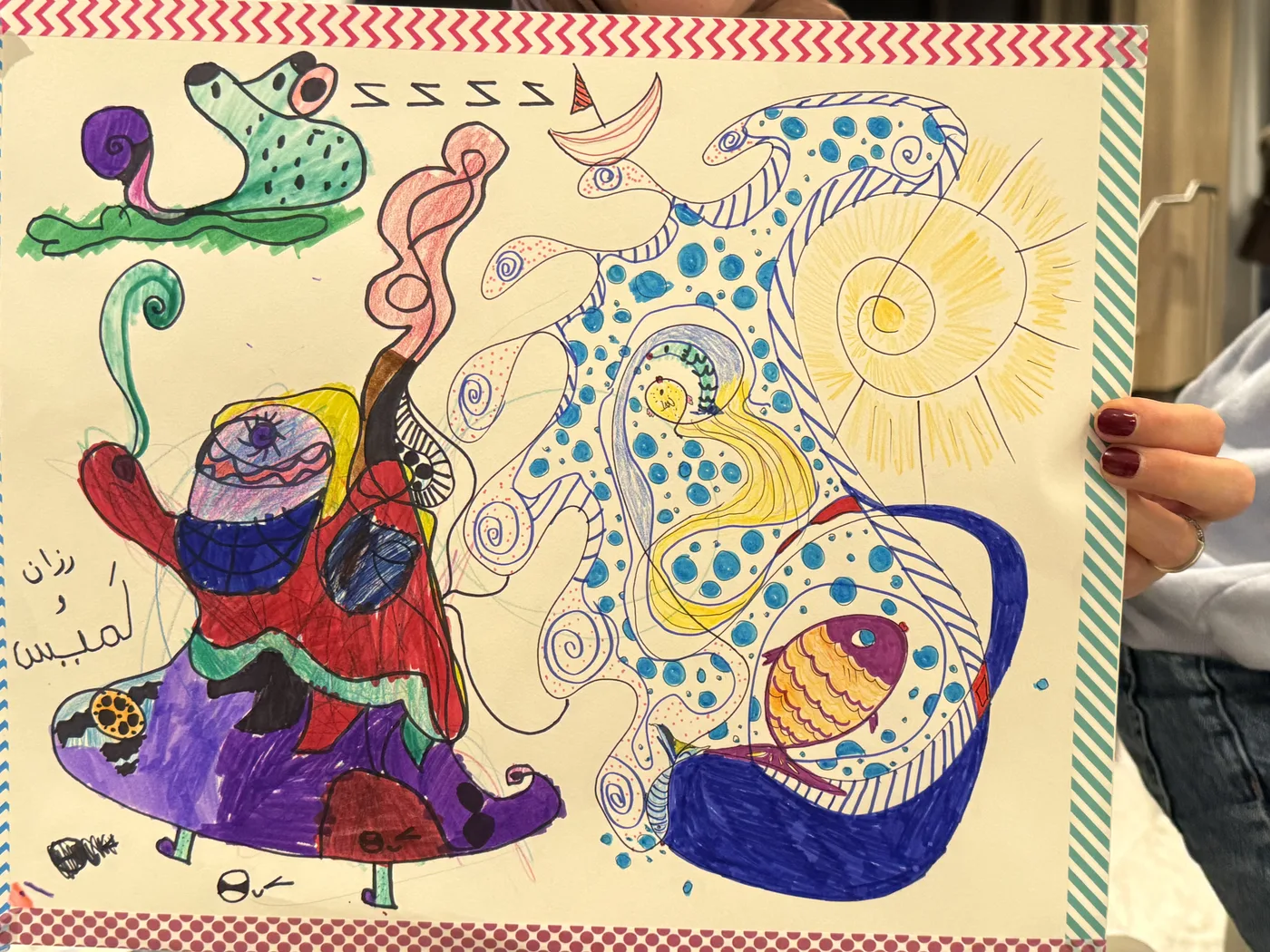 Hands holding a colourful doodle with Arabic writing