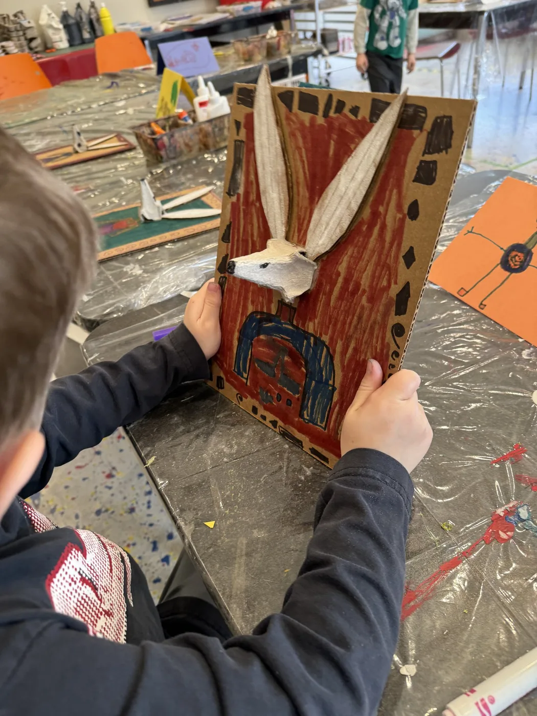 Child holding up a cardboard hare collage