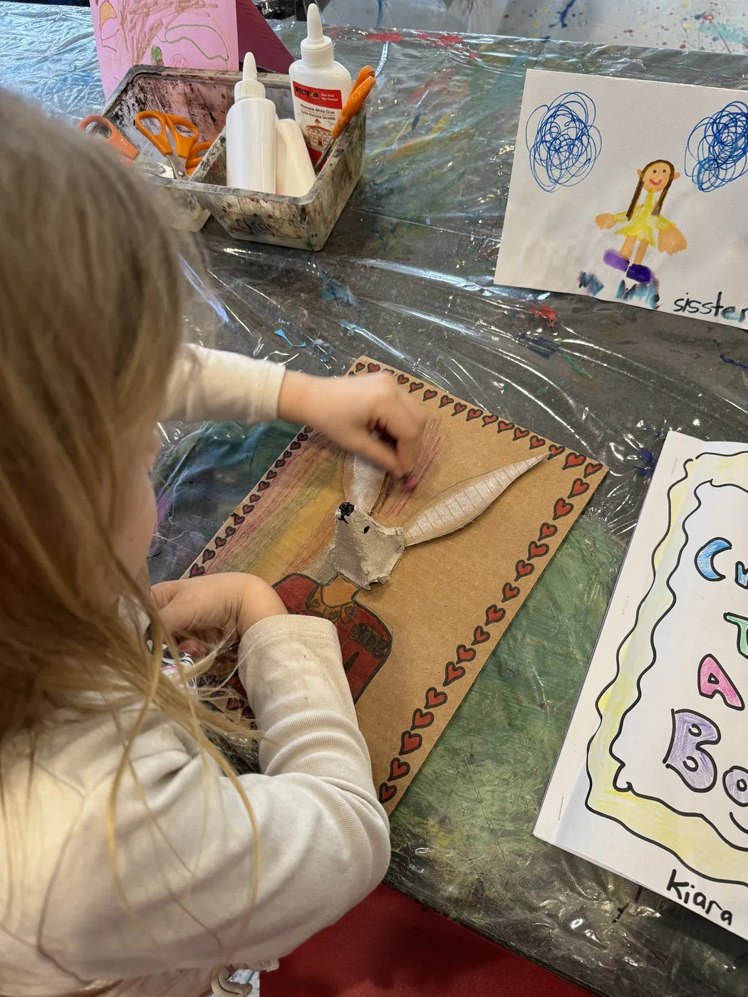 Hands shaping a cardboard hare on a collage board