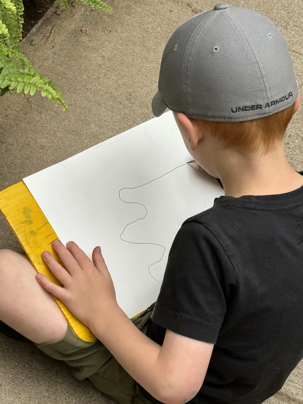 Child in a cap drawing on a clipboard