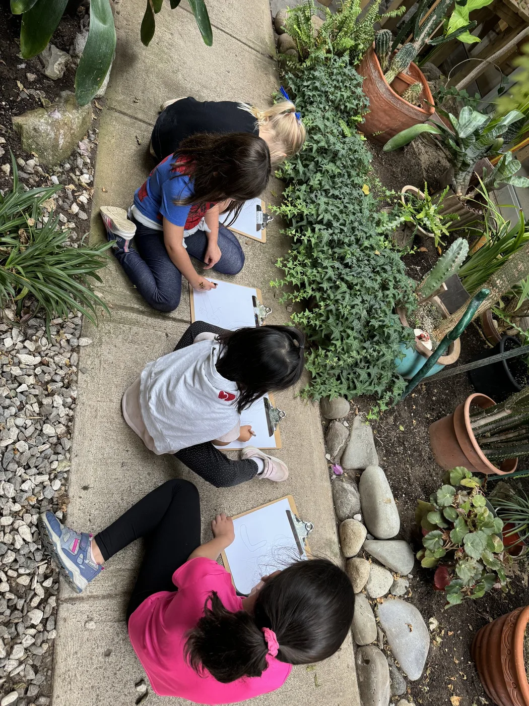 Children sketching on clipboards along a garden path