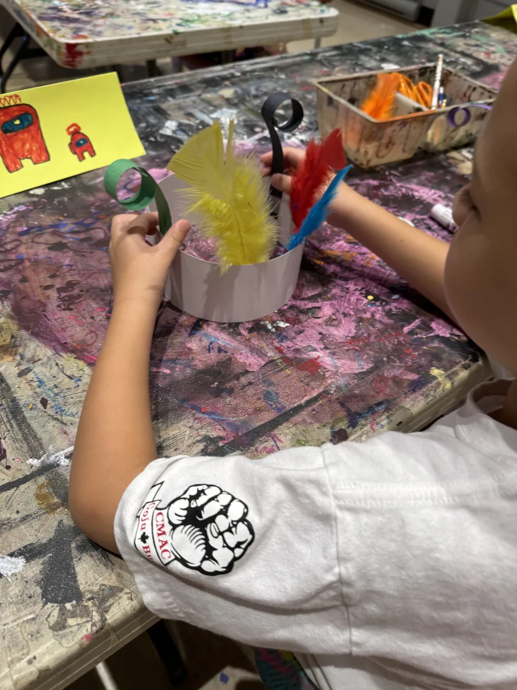 Hands adding feathers to a paper crown
