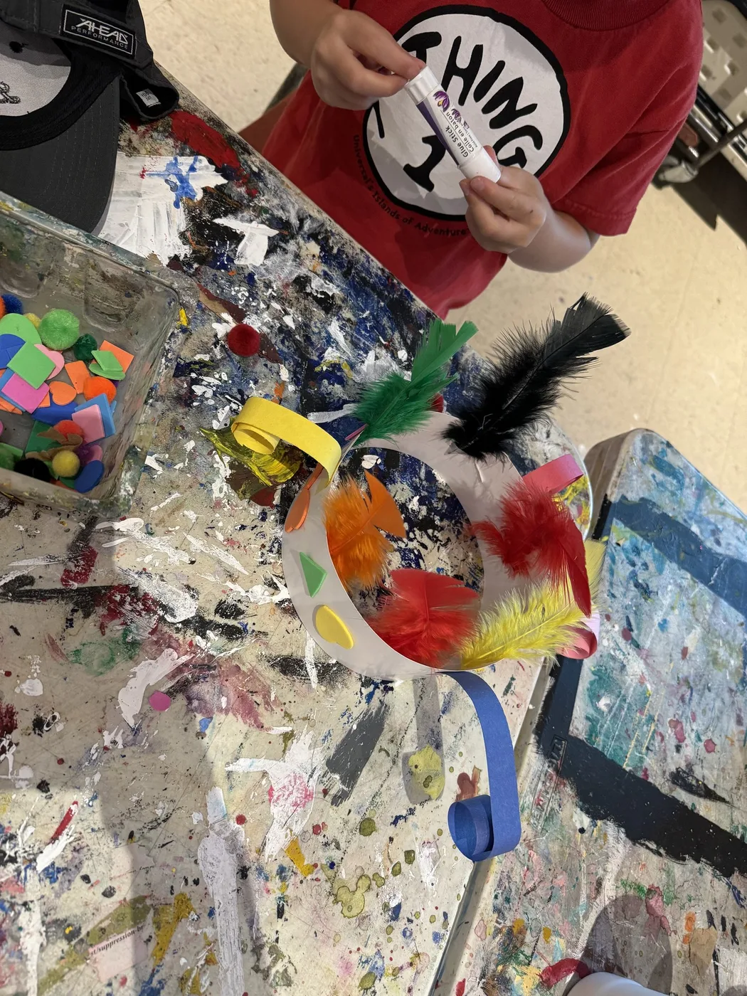 Feathered paper crown on a paint-splattered table