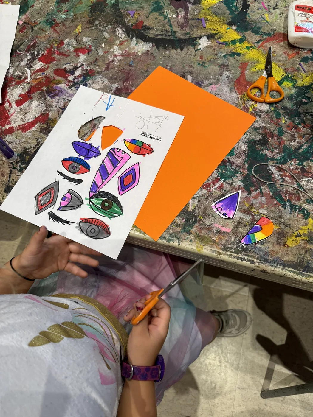 Hands cutting out coloured eye shapes