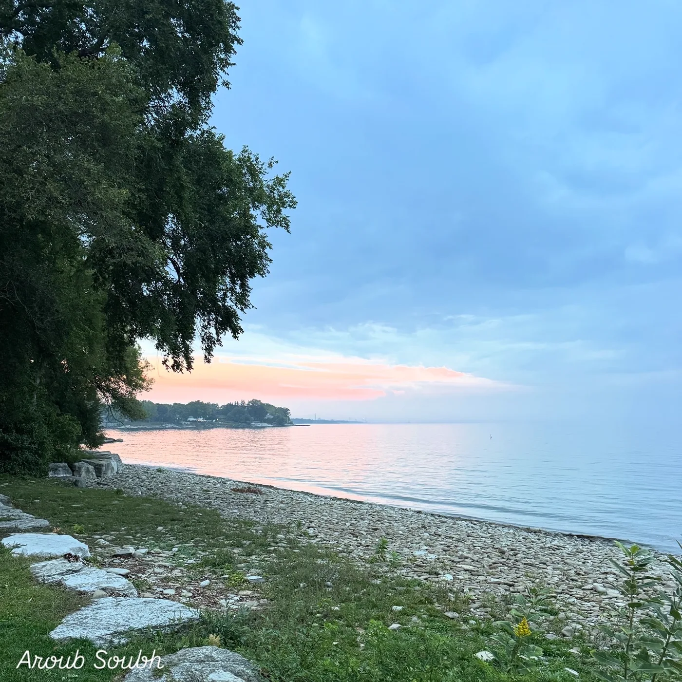A quiet shore beneath a pale blue sky
