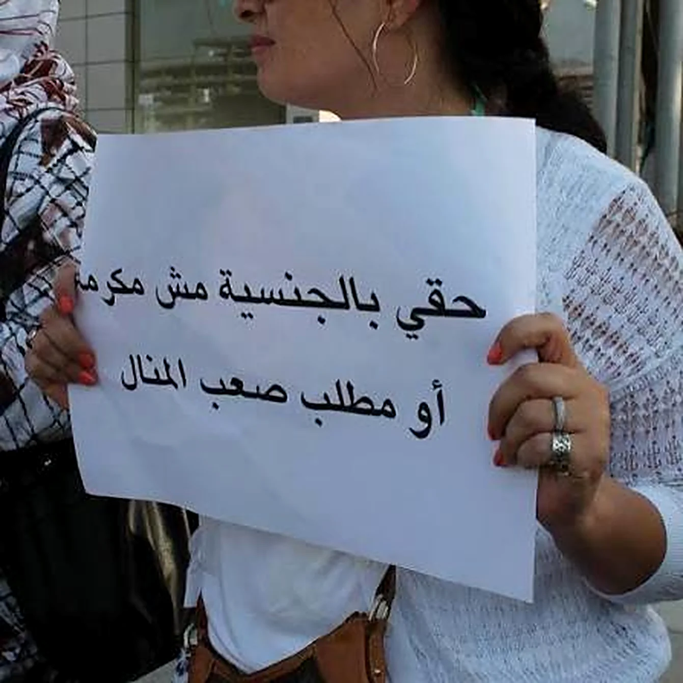 يدا عروب صبح تحملان لافتة بيضاء في وقفة احتجاجية: حقي بالجنسية مش مكرمة أو مطلب صعب المنال. من تصويرها.