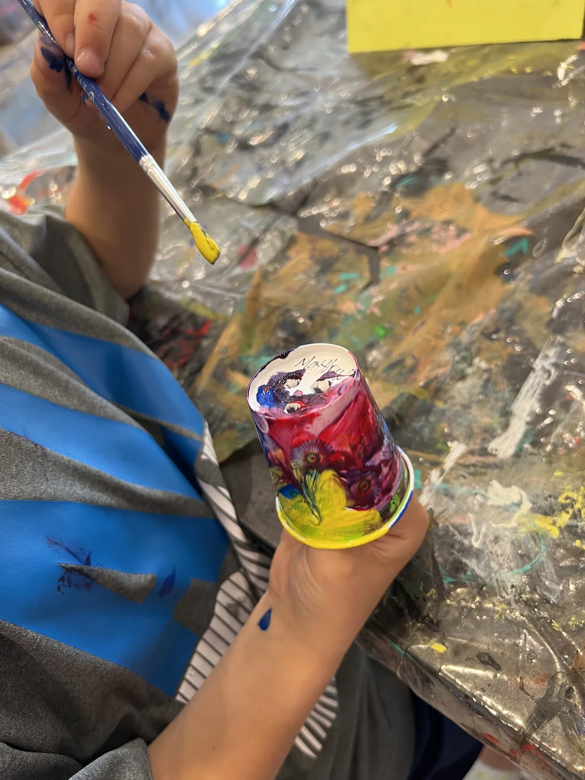 A child holding a hand-painted cup decorated with flowers