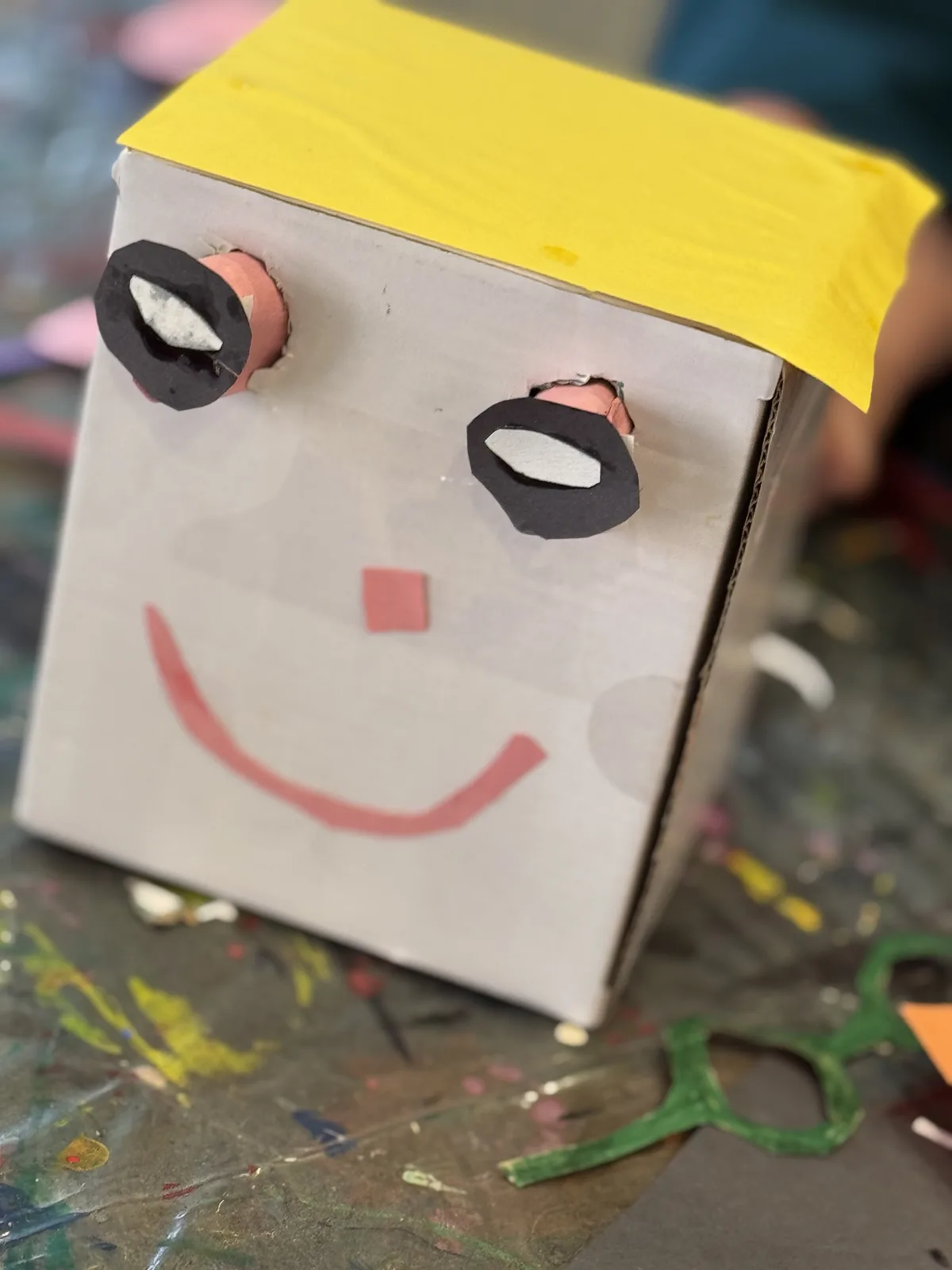 A cardboard box character craft with a painted smiling face
