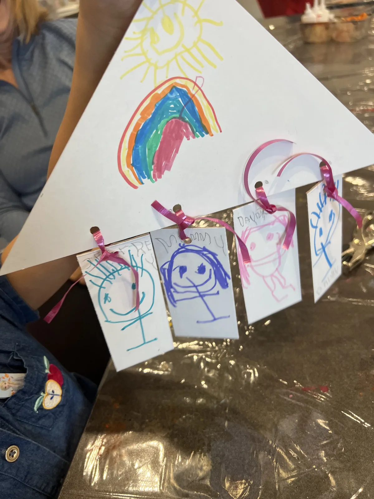 Children's rainbow drawings hung with paper-doll cutout figures