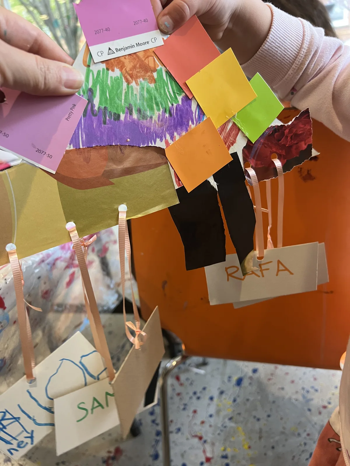 Hands assembling a colourful craft mobile with name tags