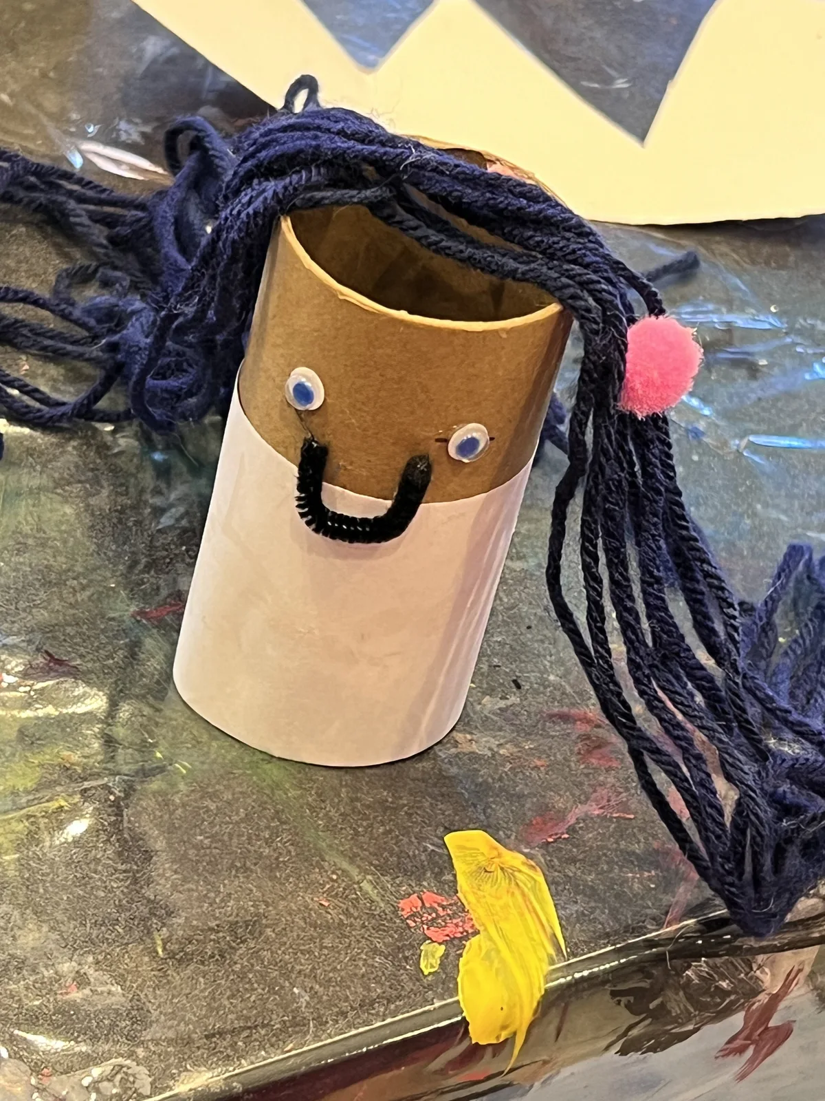 A cardboard tube face craft with black yarn hair
