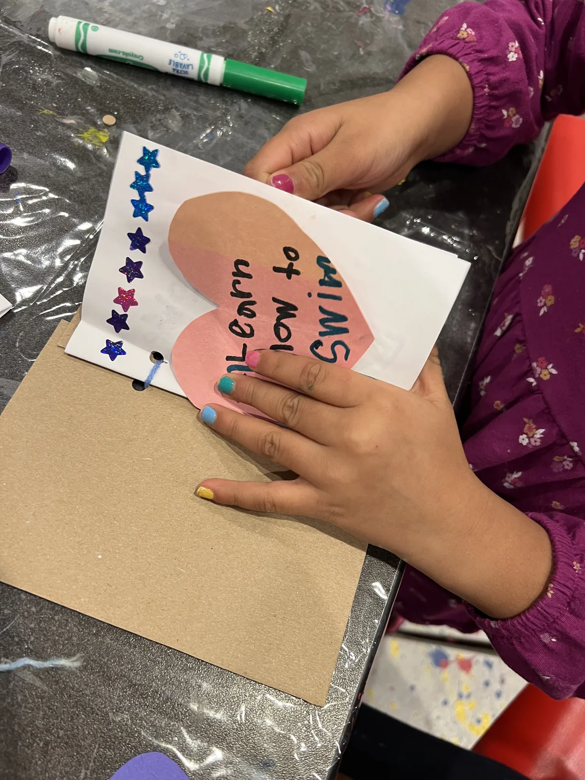 A child holding a heart-shaped wish card decorated with star stickers