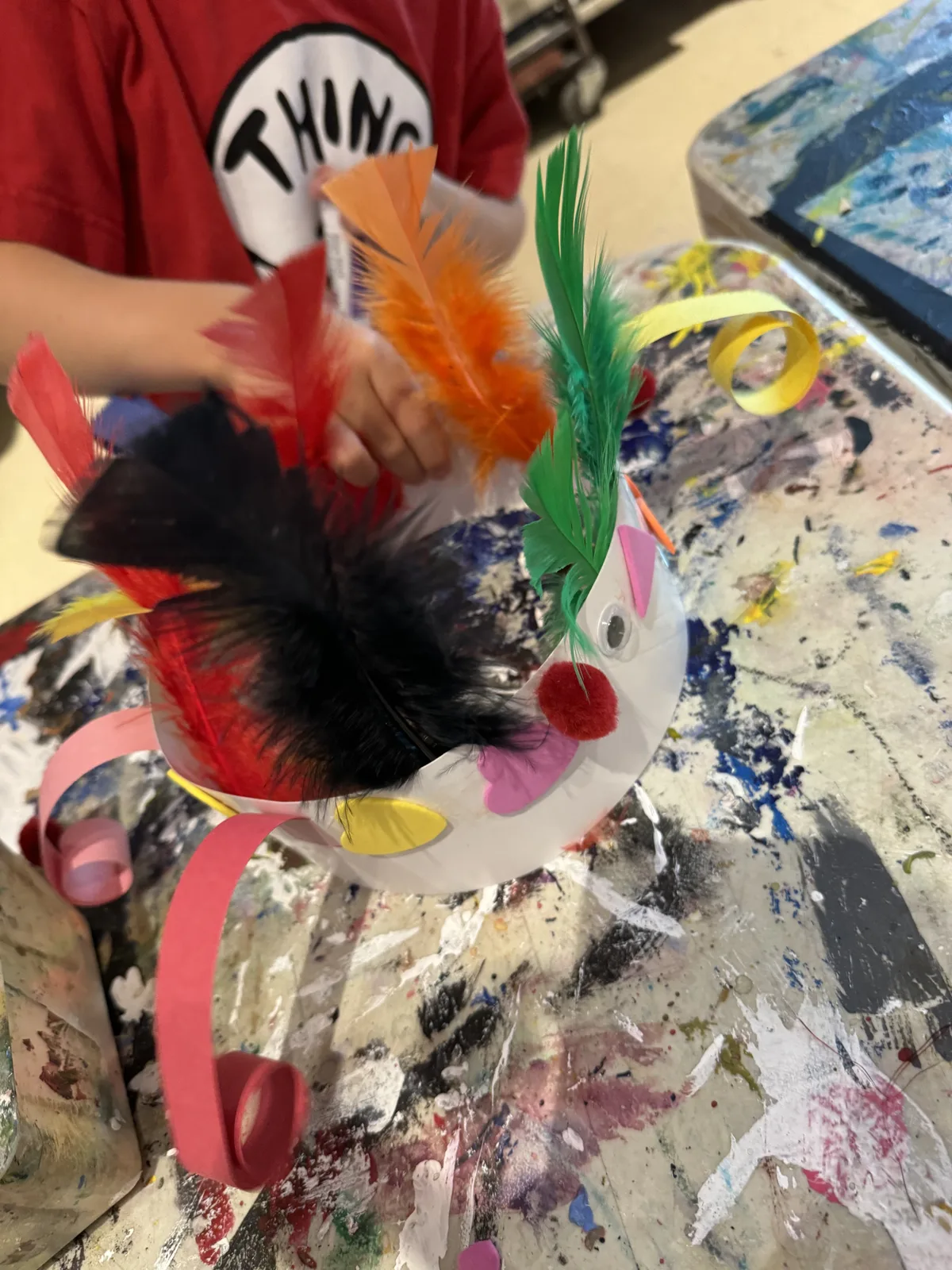 A child holding a paper crown decorated with colourful feathers