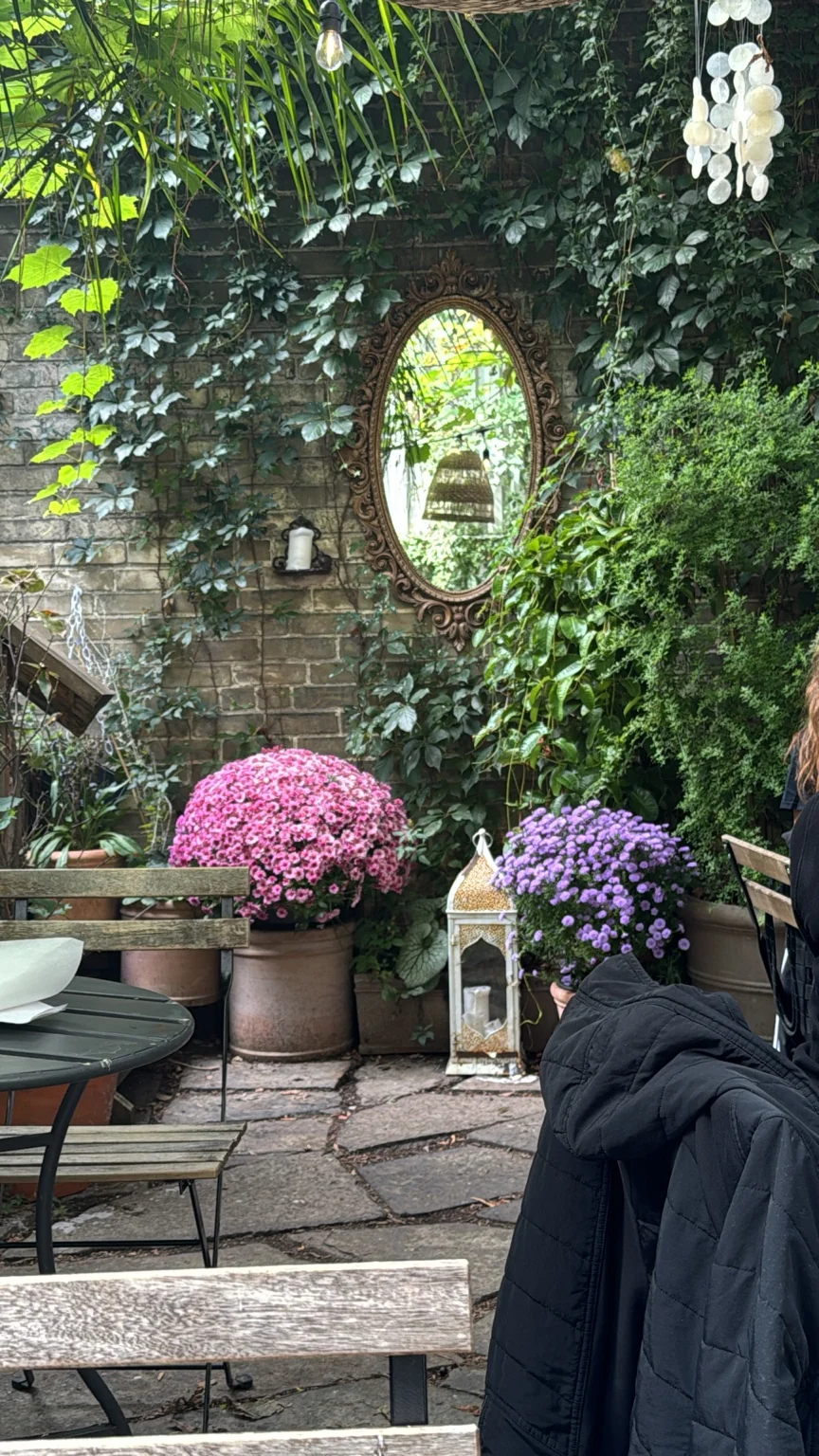 Ivy-covered courtyard with an oval mirror and flowerpots