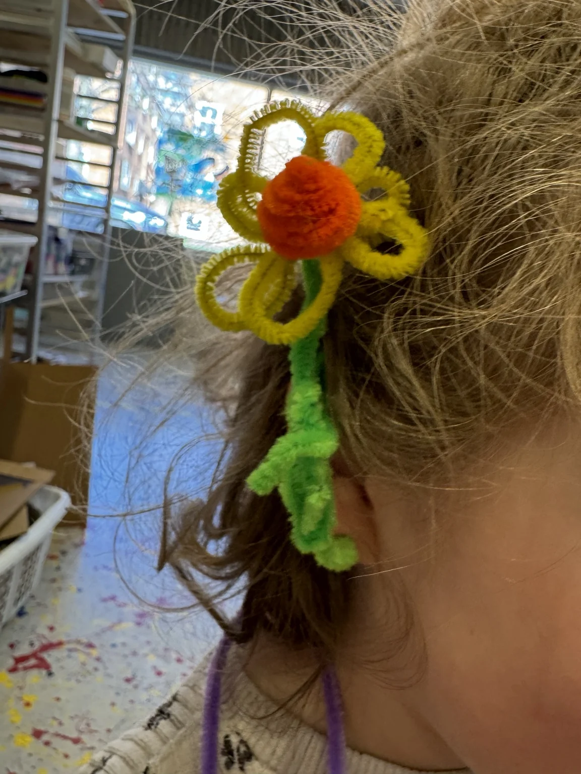 A pipe-cleaner flower clipped in hair